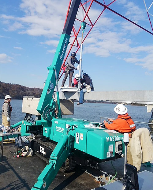 Mini-grue araignée MC305 MAEDA levant sur une barge pour les tours de TVA au Tennessee.