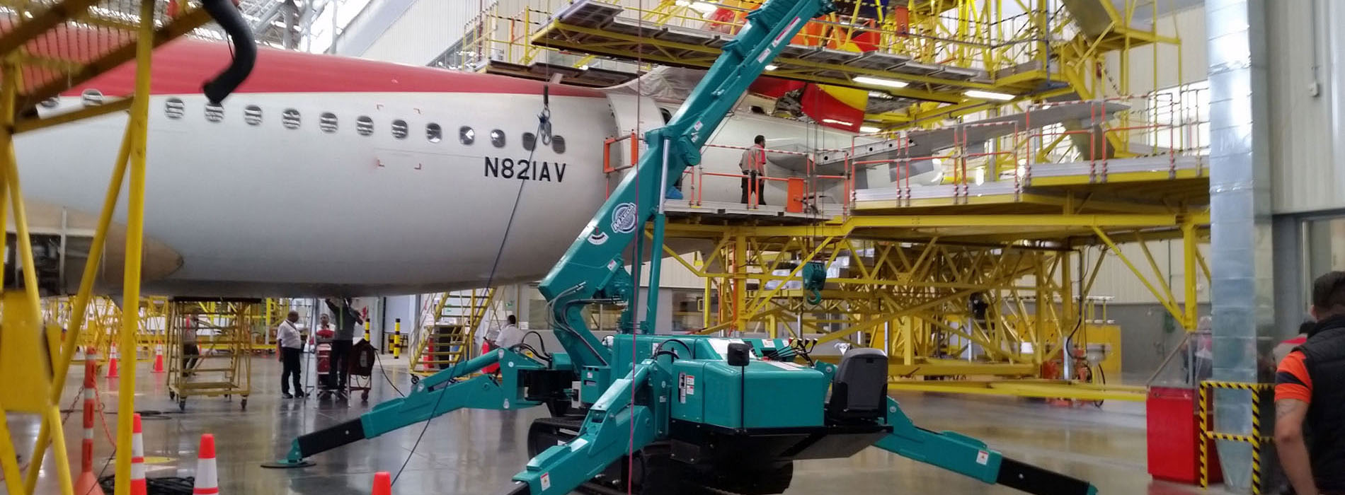 Grue araignée MAEDA travaillant sur un avion à l'intérieur des installations de maintenance
