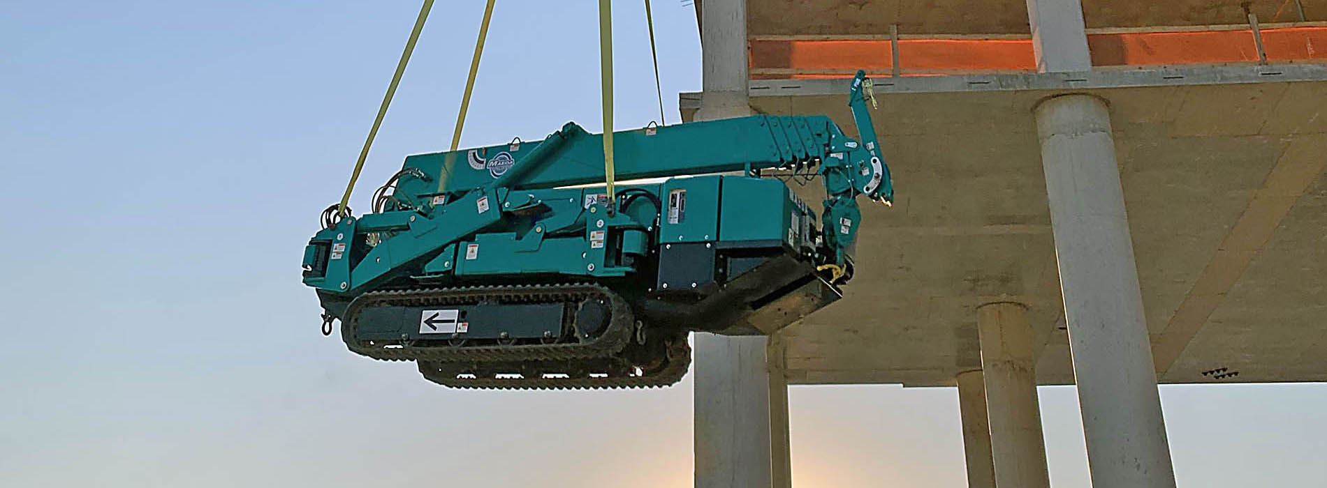 Mini-grue MAEDA en train d'être soulevée en haut du construction d'un bâtiment