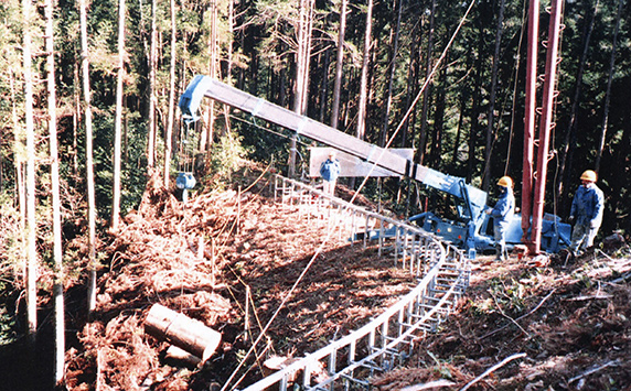 Mini-grue MAEDA soulevant des bois coupés pour un projet forestier